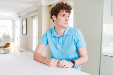 Evde rahat mavi t-shirt giyen genç yakışıklı adam kendine güvenen gülümseme ile doğal yüz pozuyla profil rahatla tarafına, seyir.