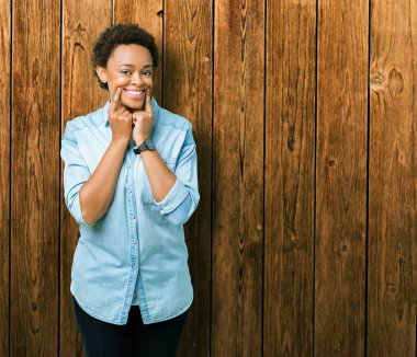 Genç güzel Afrikalı-Amerikalı kadın yüzünden izole arka plan gülen açık ağız ile parmak işaret ve neşeli gülümseme zorlamadan