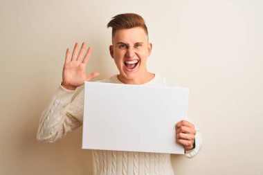 Genç yakışıklı adam izole beyaz arka plan üzerinde duran afiş tutan çok mutlu ve heyecanlı, kazanan ifade büyük bir gülümseme ile çığlık zafer kutluyor ve ellerini kaldırdı