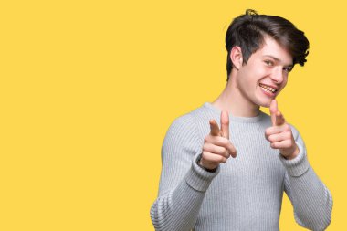 Fotoğraf makinesi ile mutlu ve komik yüz için parmakları işaret izole arka plan üzerinde kış kazak giyen genç yakışıklı adam. İyi enerji ve vibes.