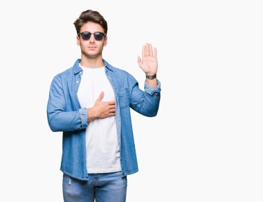 Yakışıklı delikanlı üzerinde güneş gözlüğü takıyor izole arka plan göğüs ve bir sadakat sözü yemin yapma avuç, el ile küfür