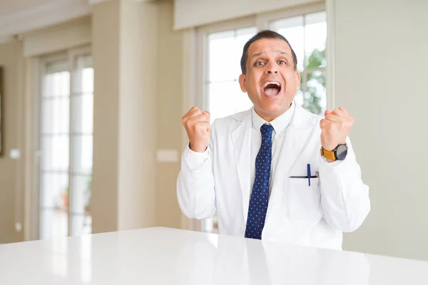 クリニックで医療コートを着た中年の医者の男性は 腕を上げて目を開けて成功したことに驚き 驚きました 勝者のコンセプト — ストック写真