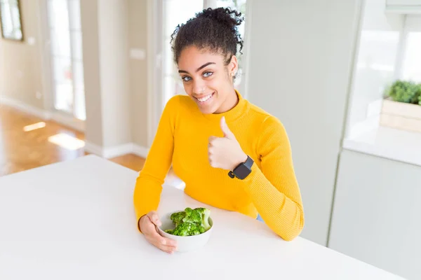 若いアフリカ系アメリカ人の女の子は 大きな笑顔で幸せな熱い緑色のブロッコリーを食べてOkサイン 指で親指アップ 優れた兆候 — ストック写真