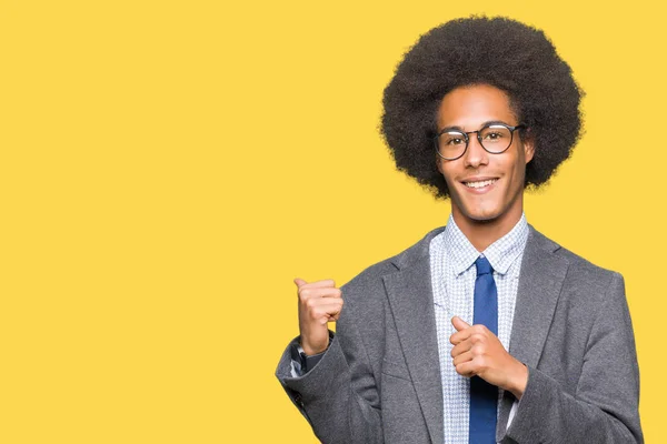 Young african american business man with afro hair wearing glasses Pointing to the back behind with hand and thumbs up, smiling confident