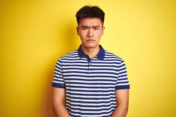 孤立した黄色の背景に立つストライプのポロを着た若いアジアの中国人男性は 問題のために動揺し 懐疑的で神経質です 否定的な人 — ストック写真