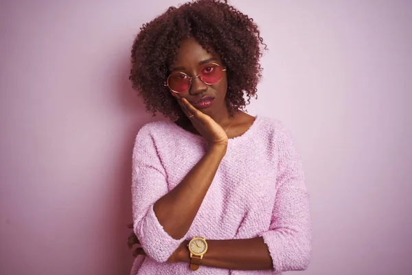 Young african afro woman wearing sweater and sunglasses over isolated pink background thinking looking tired and bored with depression problems with crossed arms.