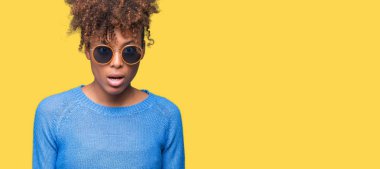 Güzel genç Afro-Amerikan kadın korkuyor ve şok sürpriz ifade, korku ve heyecan yüz ile izole arka plan üzerinde güneş gözlüğü takıyor.