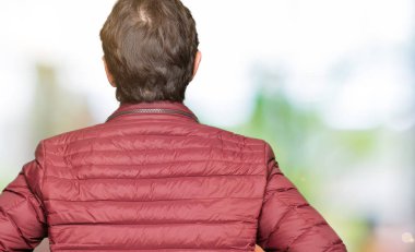 Gözlük ve geriye doğru uzakta silah ile vücut üzerinde seyir ayakta kış ceket giyen orta yaş yakışıklı adam