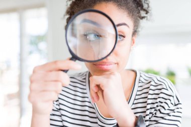 Genç afro-amerikan kadın büyüteç ciddi yüz soru hakkında düşünme bakarak, çok karışık bir fikir