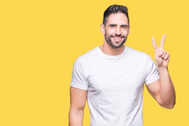 Gösterilen ve parmakları ile işaret izole arka plan üzerinde rahat beyaz t-shirt giyen genç adam ikincisi ise kendinden emin ve mutlu gülümseyerek.