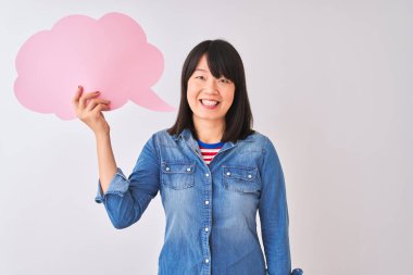 Genç güzel Çinli kadın mutlu bir yüz ayakta ve dişleri gösteren kendinden emin bir gülümseme ile gülümseyerek izole beyaz arka plan üzerinde bulut konuşma balonu tutan