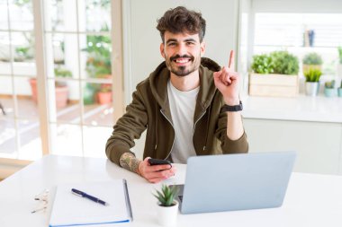 Akıllı telefon kullanan ve dizüstü bilgisayar kullanarak eğitim genç öğrenci mutlu yüz, bir numaralı ile bir fikir veya soru işaret parmağı ile şaşırttı