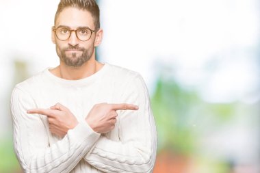 Genç yakışıklı adam gözlük izole üzerinde işaretleme için her iki parmak, farklı yönde ile katılmıyorum arka plan
