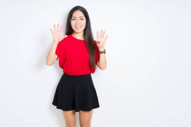 İzole arka plan üzerinde kırmızı t-shirt ve etek giyen güzel esmer kadın gösteren ve emin ve mutlu gülümserken parmakları ile dokuz numara işaret.