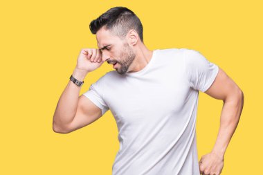 Yakışıklı adam sarı izole arka plan üzerinde beyaz t-shirt giyen geri uzanan, yorgun ve rahat, uykulu ve erken sabah için esneme