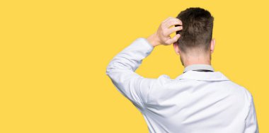 Tıbbi ceket giymiş genç yakışıklı Doktor adam geriye el ile şüphe hakkında düşünme