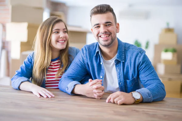 Young beautiful couple sitting on the table at home, hugging in