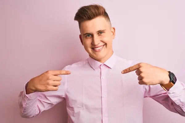 若いハンサムなビジネスマンは 顔に笑顔で自信を持って見て 誇りに思って幸せな指で自分自身を指して 孤立したピンクの背景の上に立ってエレガントなシャツを着て — ストック写真