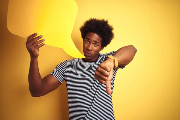 若いアフリカ系アメリカ人男性が怒った顔で孤立した黄色の背景の上に立つスピーチバブルを保持し 親指を下にして嫌いを示す否定的な兆候 拒絶概念 — ストック写真