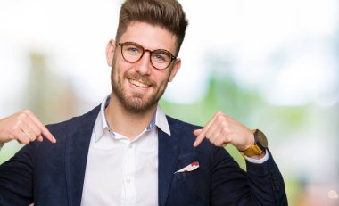 Yüzünde gülümseme ile kendinden emin görünüyorsun, kendini gururlu ve mutlu parmakları ile işaret gözlüklü genç yakışıklı iş adamı.