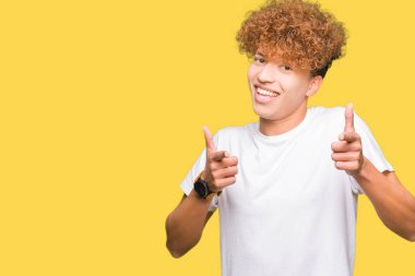 Fotoğraf makinesi ile mutlu ve komik yüz için rahat beyaz t-shirt işaret parmakları giyen afro saçlı Genç yakışıklı adam. İyi enerji ve vibes.