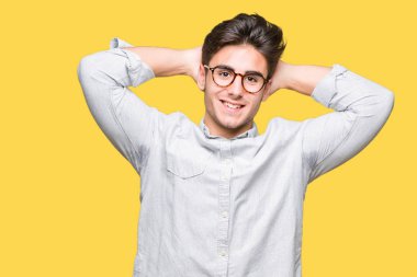 Genç yakışıklı adam gözlük izole üzerinde arka plan dinlenirken ve germe kollar ve eller baş ve boyun arkasında ile mutlu gülümseyerek