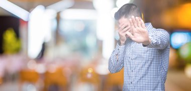 Genç yakışıklı adam izole elleriyle gözlerini kapsayan arka plan ve stop jest ile acı ve korku ifadesi. Utandım ve negatif kavramı.