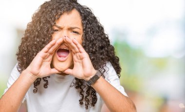 Eller genç güzel kadın kıvırcık saçlı kızgındım yüksek sesle bağırarak beyaz t-shirt giyen ağzına