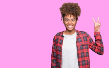 Güzel genç Afro-Amerikan kadın gözlük gösterilen ve parmakları ile işaret izole arka plan üzerinde kendinden emin ve mutlu gülümseyerek iken ikincisi.