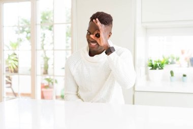 Yakışıklı afro-amerikan adam beyaz masada el gülümseyerek ok jest yapıyor, mutlu yüz ile parmakları ile bakarak göz.