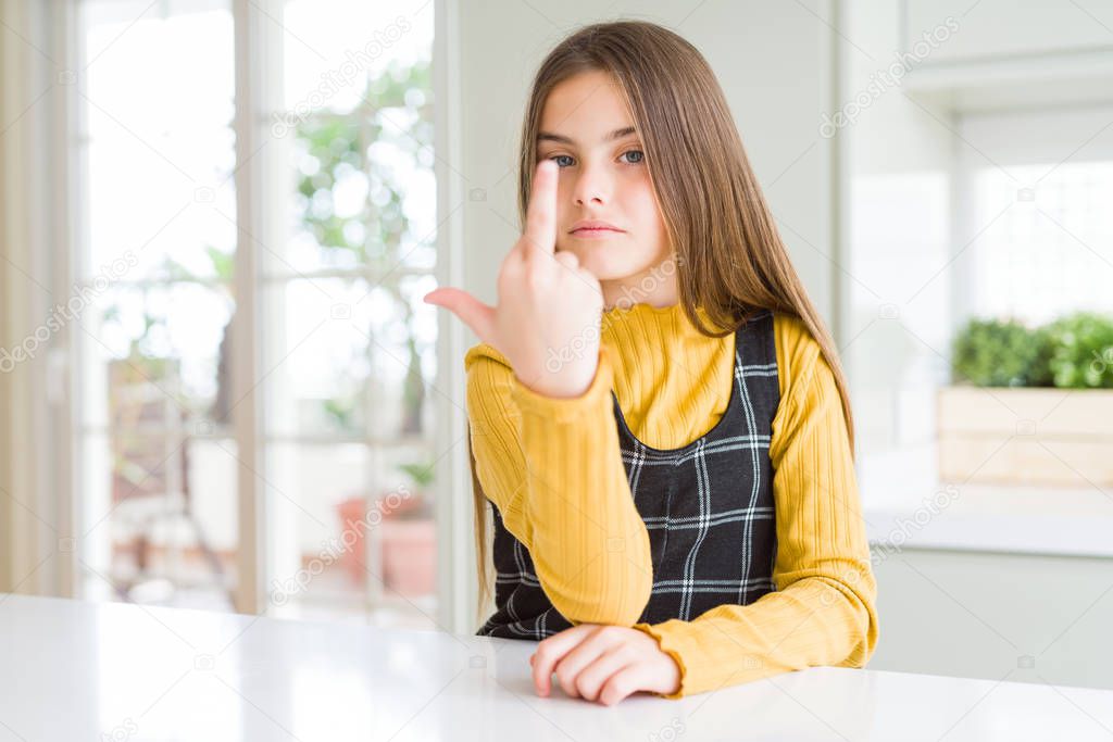 Young beautiful blonde kid girl wearing casual yellow sweater at home Showing middle finger, impolite and rude fuck off expression