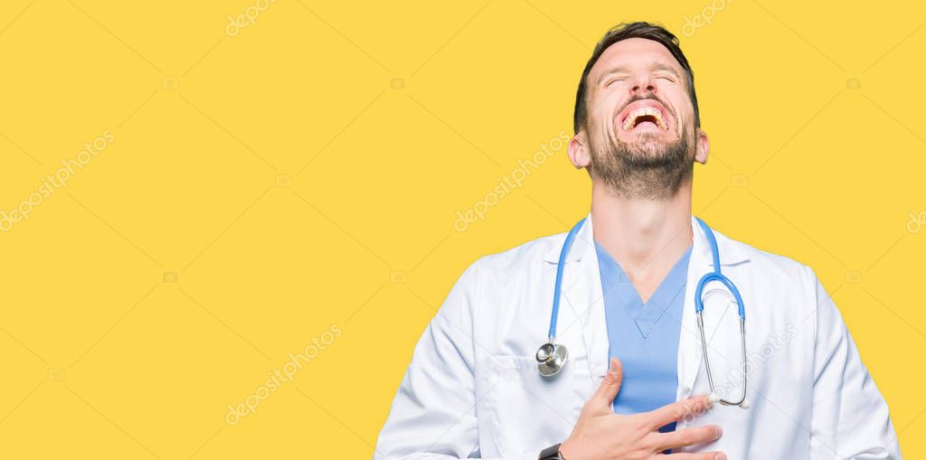 Handsome doctor man wearing medical uniform over isolated background Smiling and laughing hard out loud because funny crazy joke. Happy expression.