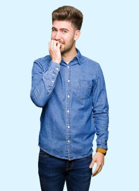 Genç yakışıklı sarışın adam stresli ve gergin ile rahat kot gömlek giymiş tırnak ısırma dudaklarından eller. Anksiyete sorunu.