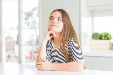 Güzel genç kız çocuk çizgili t-shirt giyen çene üzerinde el ile soru, dalgın ifade düşünme. Düşünceli bir yüzle gülümsüyor. Şüphe kavramı.