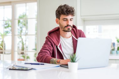 Genç öğrenci bilgisayar dizüstü bilgisayar ve dizüstü bilgisayar kullanarak akıllı yüz ciddi düşünme kendine güvenen bir ifade ile
