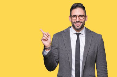 Kameraya bakarak yan el ve parmak ile işaret eden genç yakışıklı iş adamı yüzünde kocaman bir gülümseme ile izole arka plan üzerinde.