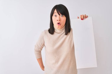 Genç güzel Çinli kadın izole beyaz arka plan üzerinde asılı afiş tutan sürpriz bir yüz ile şok korkmuş, korku ve korku ifade ile heyecanlı