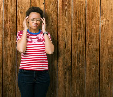 Güzel genç Afro-Amerikan kadın gözlük ile izole arka plan üzerinde baş ağrısı için kafasına çünkü el stres. Migren muzdarip.