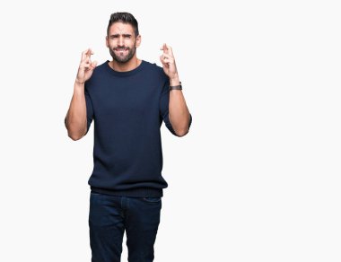 Genç yakışıklı adam izole arka plan üzerinde umut ve gözleri kapalı geçiş parmakları üzerinde kazak giyiyor. Şans ve batıl kavram.