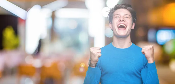 Jovem Homem Bonito Vestindo Camisola Azul Sobre Fundo Isolado Comemorando — Fotografia de Stock