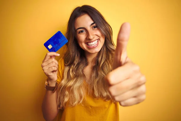 Joven Hermosa Mujer Sosteniendo Tarjeta Crédito Sobre Fondo Aislado Amarillo —  Fotos de Stock