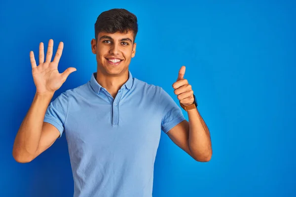 カジュアルなポロを着た若いインド人男性が 自信を持って幸せそうに微笑みながら 6番の指を見せ 指で指を上げている — ストック写真