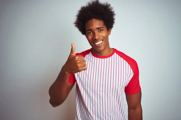 African american man with afro hair wearing red striped t-shirt over isolated white background doing happy thumbs up gesture with hand. Approving expression looking at the camera with showing success.