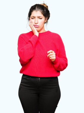 Kırmızı kazak ve diş ağrısı veya dişlerde dişlerle ilgili hastalık nedeniyle ağız acı ifadesi ile el ile dokunmak topuz giyen genç güzel kadın. Diş hekimi kavramı.