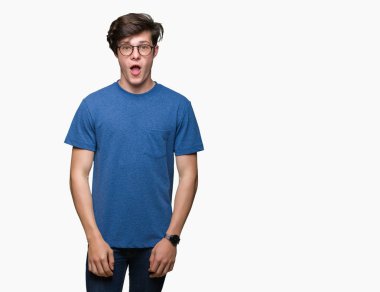 Korkuyor ve şok sürpriz ifade, korku ve heyecan yüz ile izole arka plan üzerinde gözlük takan genç yakışıklı adam.