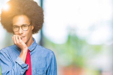Afro saçlı ve kırmızı kravat takan afro-amerikalı genç iş adamı, elleri ağzı yla tırnakları ısırarak stresli ve gergin görünüyor. Anksiyete sorunu.