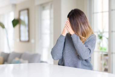 Yüzünü elleriyle ağlayarak süre kapsayan üzgün ifade ile kış kazak evde giyen genç güzel kadın. Depresyon kavramı.