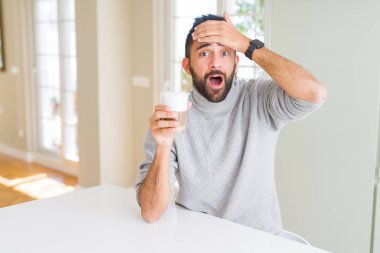 Yakışıklı İspanyol adam başında el ile stresli bir fincan kahve içme, utanç ve sürpriz yüz ile şok, kızgın ve sinirli. Korku ve hata için üzgün.