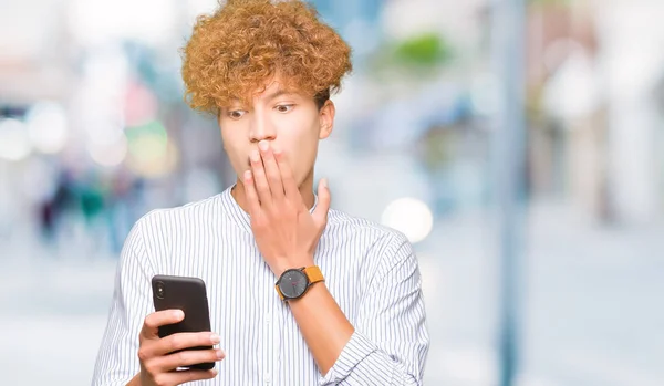 Jovem Homem Bonito Usando Boca Capa Smartphone Com Mão Chocada — Fotografia de Stock