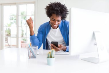 Afro-Amerikan adam akıllı telefon ve bilgisayar kullanarak çalışan gurur çığlık ve zafer ve başarı çok heyecanlı kutluyor, duygu tezahürat